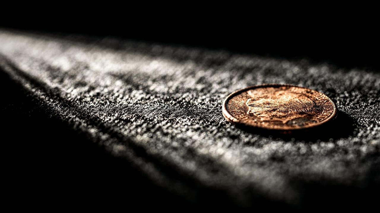 A single worn copper penny displayed on black velvet under a harsh museum spotlight, like a retired relic.